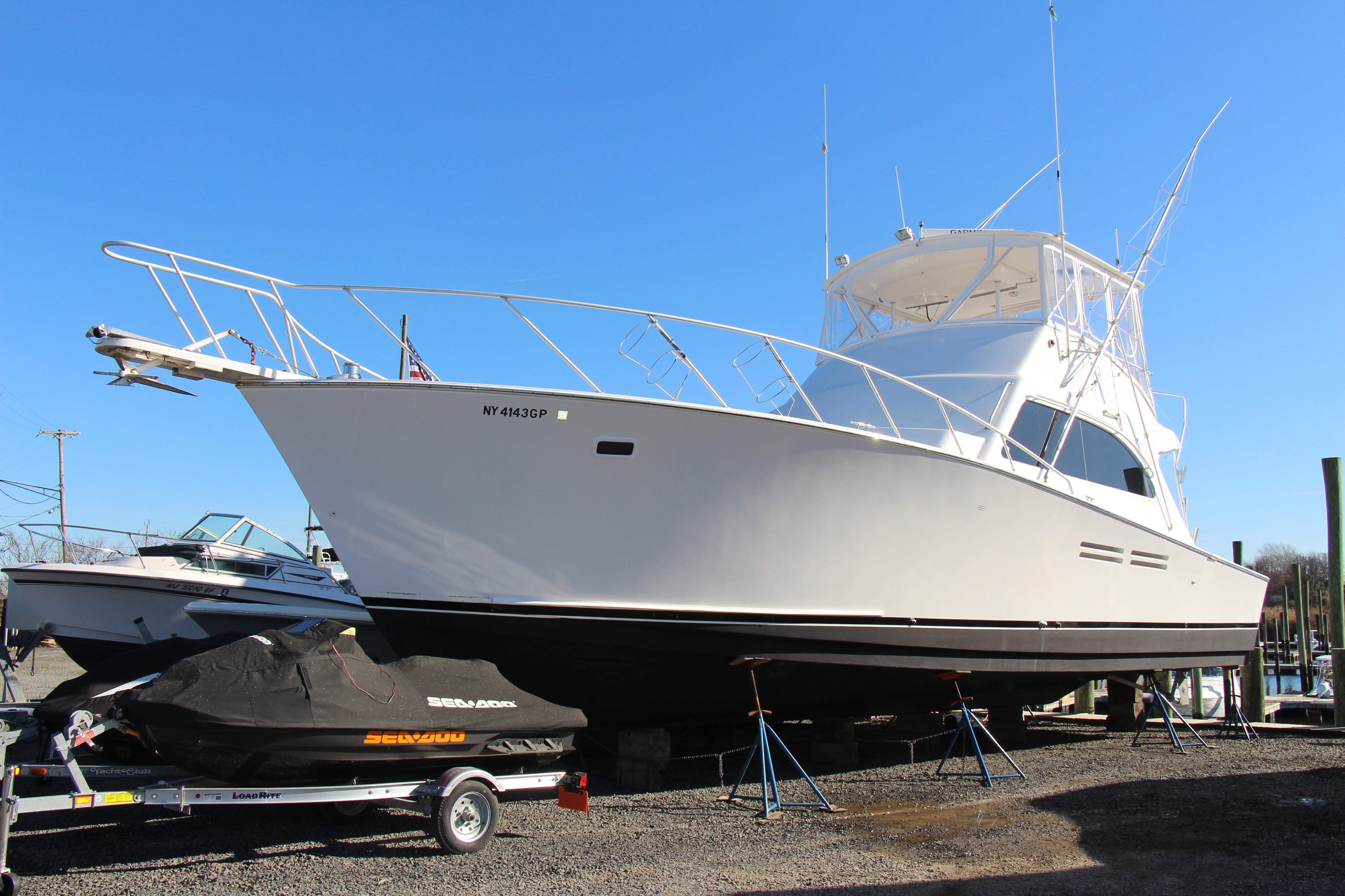 White 2000 Post 50 yacht on dry dock with a covered jet ski nearby.