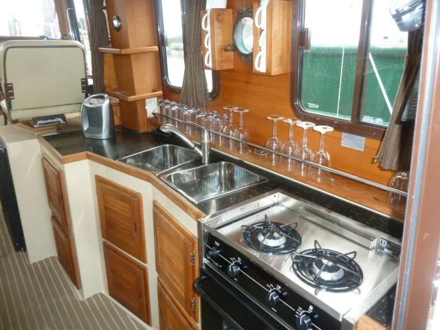 Island Wanderer Yacht Photos Pics Interior of 2013 Ranger Tugs R-31 boat kitchen with stove, sink, and wooden cabinets.