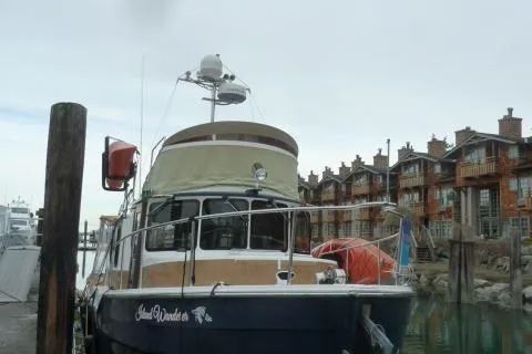 Island Wanderer Yacht Photos Pics 2013 Ranger Tugs R-31 boat docked near rustic waterfront buildings.