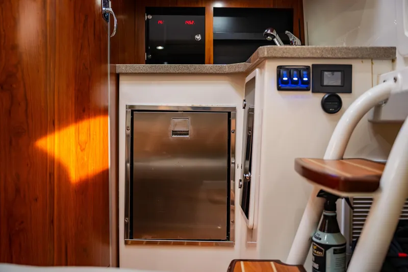  Yacht Photos Pics 2018 Regulator 41 boat interior with stainless steel fridge, wooden cabinetry, and control panel.