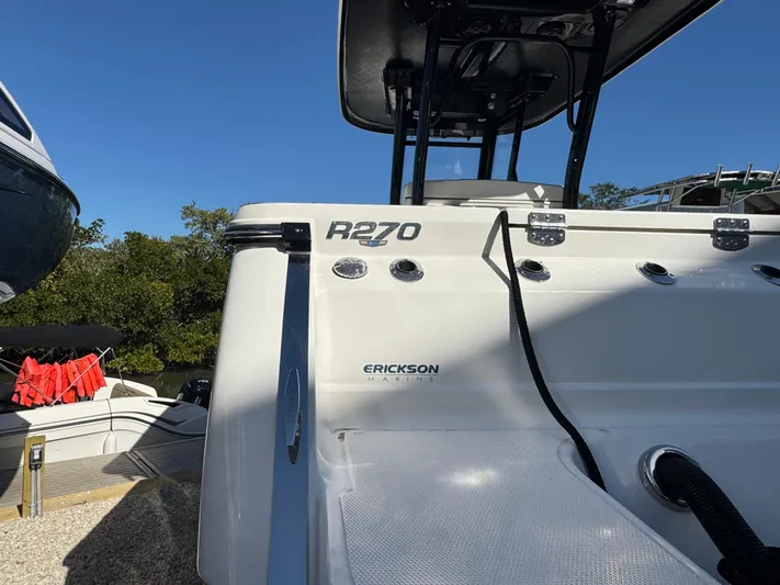  Yacht Photos Pics 2023 Robalo R270 Center Console boat, rear view, docked under clear blue sky.