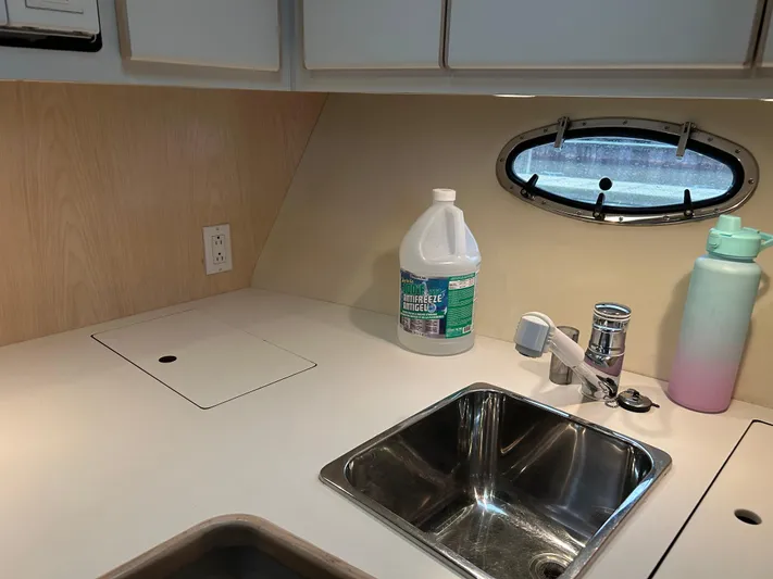 Matilda Bay Yacht Photos Pics 1997 Tiara Yachts 3500 Express kitchen area with sink, cleaning supplies, and porthole window.