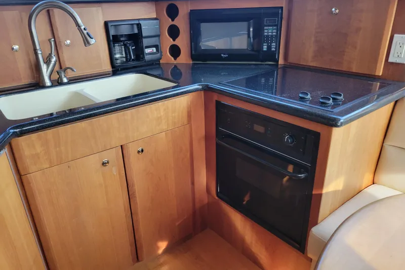 Escape II Sea Yacht Photos Pics 2003 Silverton 453 Motor Yacht kitchen with sink, microwave, oven, and wooden cabinetry.