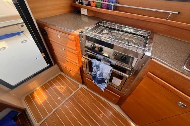 Windless Yacht Photos Pics 2016 Ranger Tugs R-29 S Tug kitchen with stove, wooden cabinetry, and countertop.