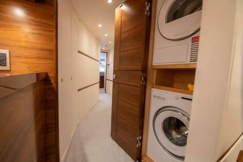 Caballo Grande Yacht Photos Pics Laundry area inside 2024 Viking 68 Enclosed Bridge yacht, featuring modern appliances and wood paneling.