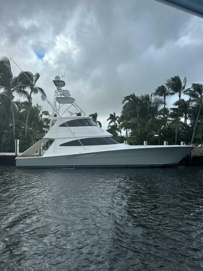 Caballo Grande Yacht Photos Pics 2024 Viking 68 Enclosed Bridge yacht docked near palm trees under cloudy skies.