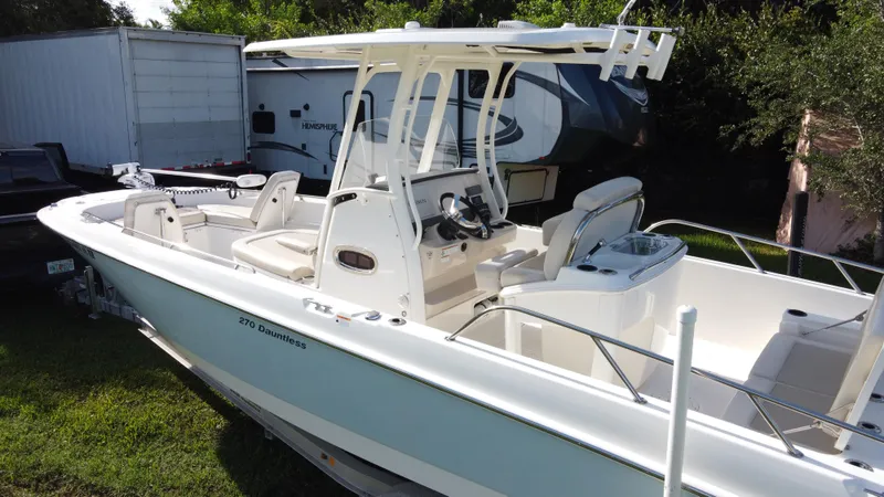  Yacht Photos Pics 2020 Boston Whaler 270 Dauntless boat, white exterior, parked on grass near trailers.
