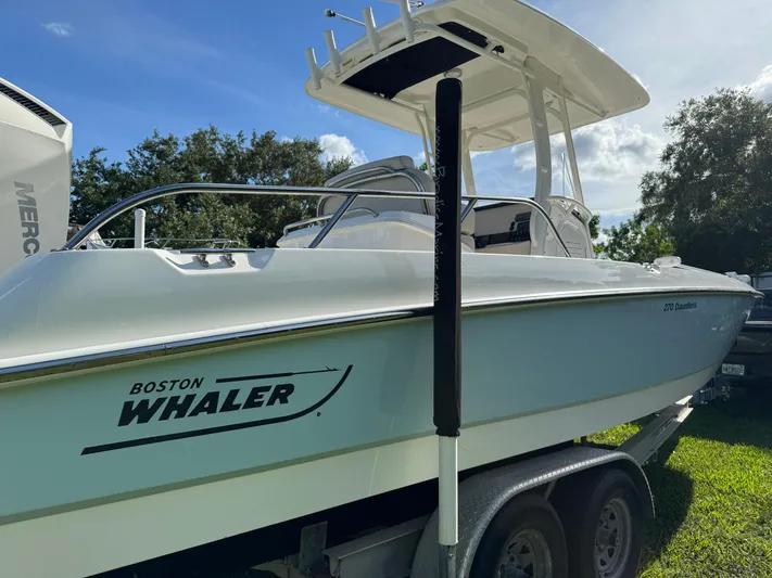  Yacht Photos Pics 2020 Boston Whaler 270 Dauntless boat on trailer, sunny day, trees in background.