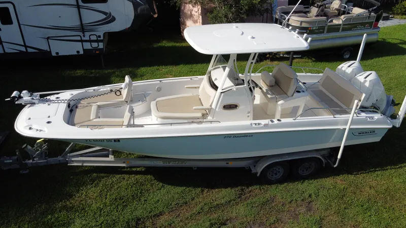  Yacht Photos Pics 2020 Boston Whaler 270 Dauntless boat on trailer, parked on grass.