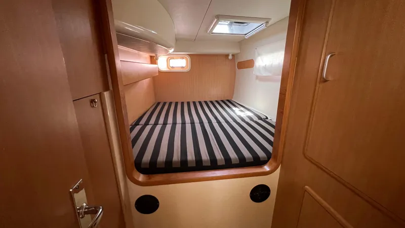 1687 Yacht Photos Pics Cozy cabin interior of 2006 Leopard 40 catamaran with striped bedding and wooden finish.