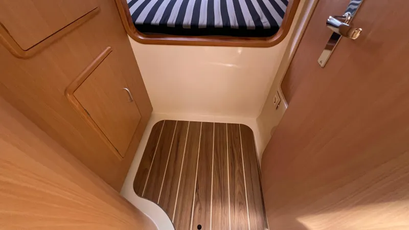 1687 Yacht Photos Pics Interior of a 2006 Leopard 40 yacht, featuring wood flooring and a striped bed.