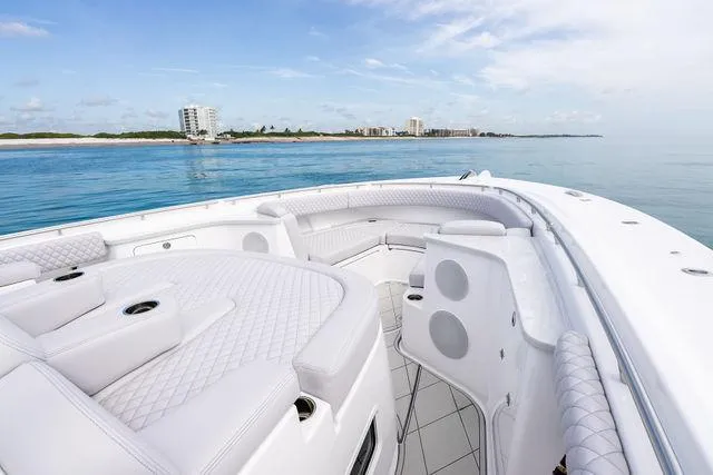 Bushwacked Yacht Photos Pics Luxury 2025 HCB 56 Suenos GIX boat with elegant seating, cruising near a coastal skyline.