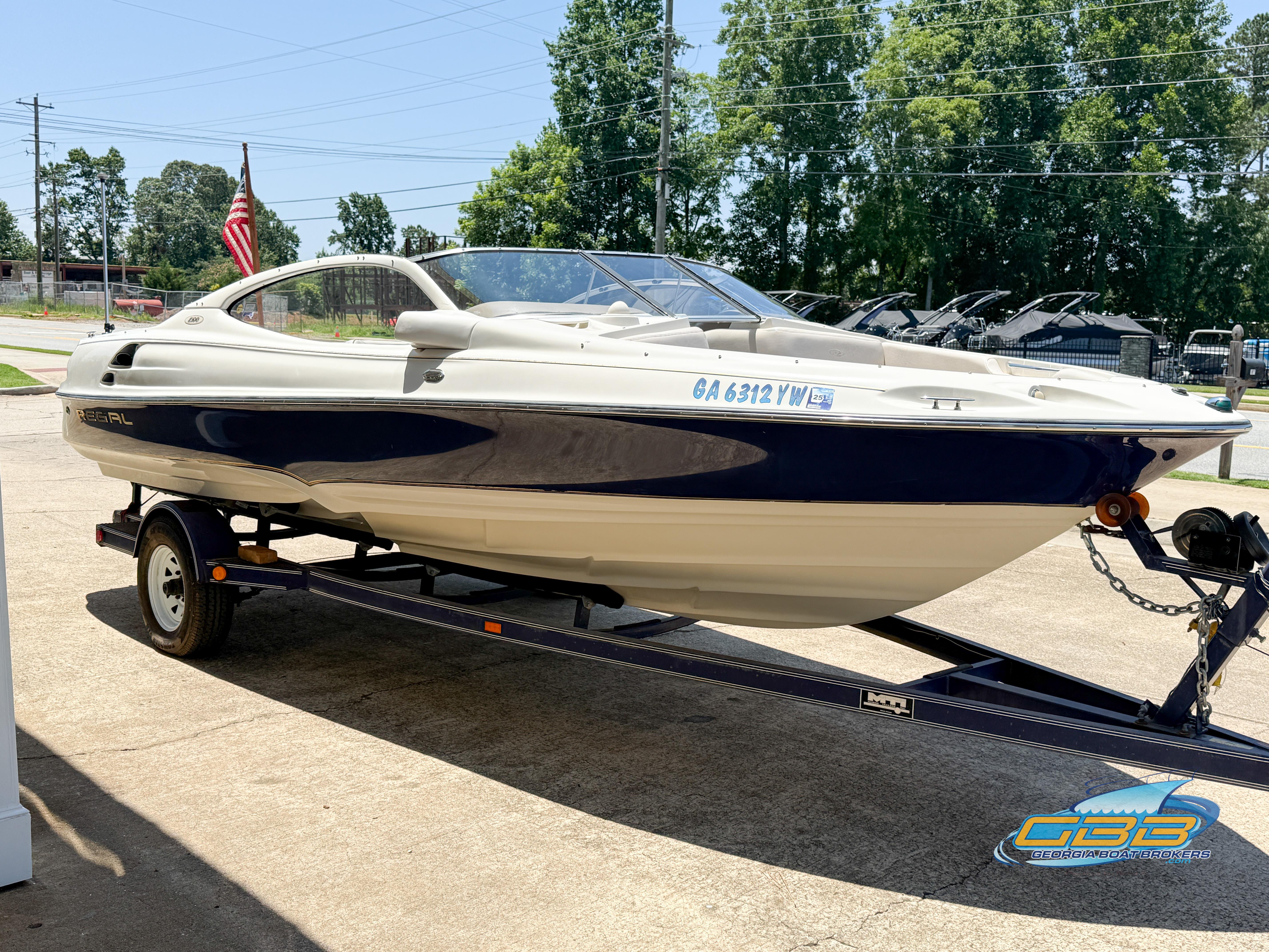 1998 Regal 2100 LSR boat on trailer, parked outdoors with trees in background.