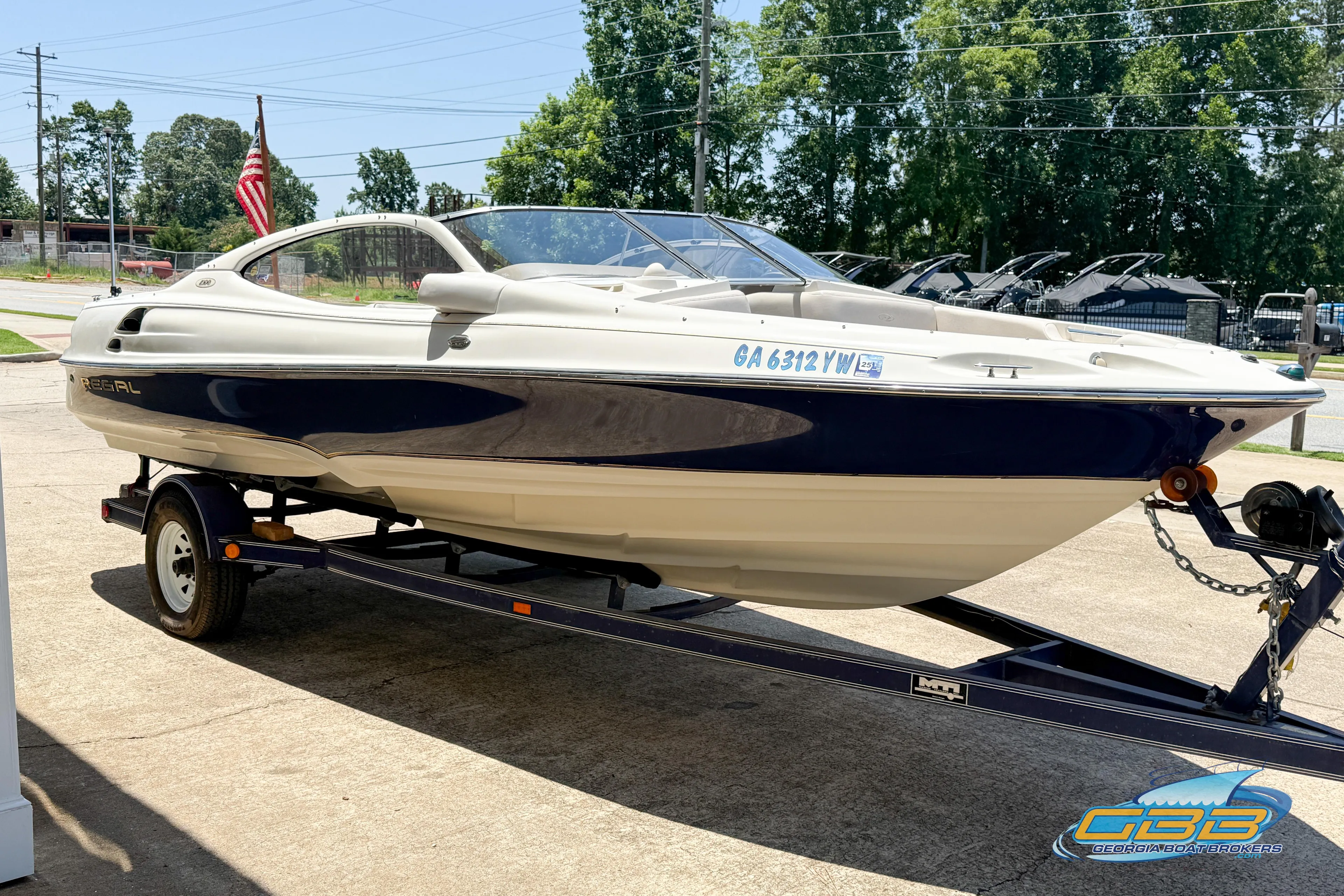 1998 Regal 2100 LSR boat on trailer, parked outdoors with trees in background.