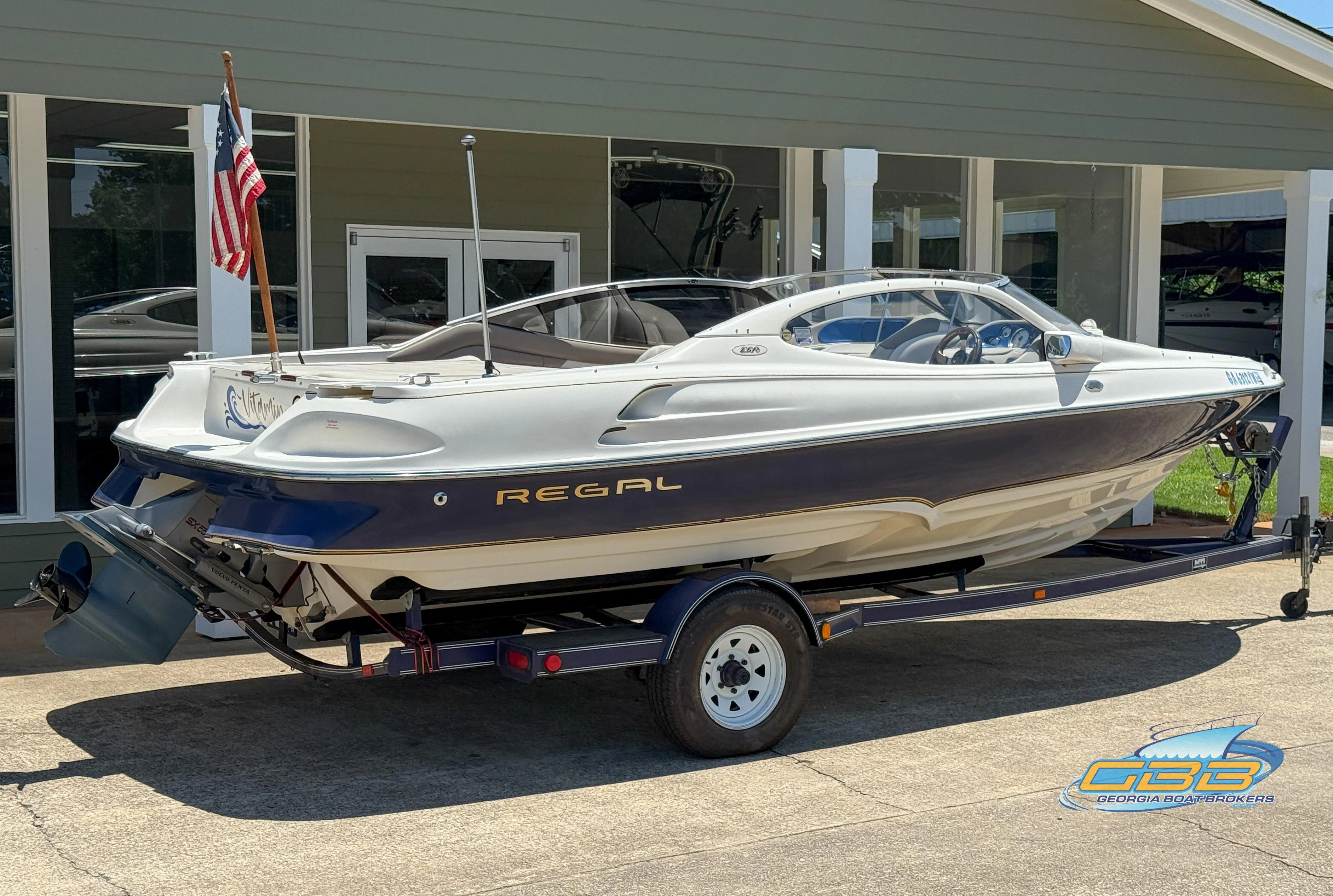 1998 Regal 2100 LSR boat on trailer, parked outside a building with an American flag.