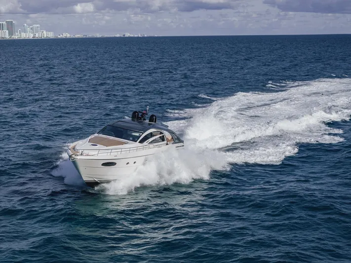 Pershing 70 White Yacht Photos Pics 2016 Pershing 70 yacht cruising on open ocean with city skyline in background.