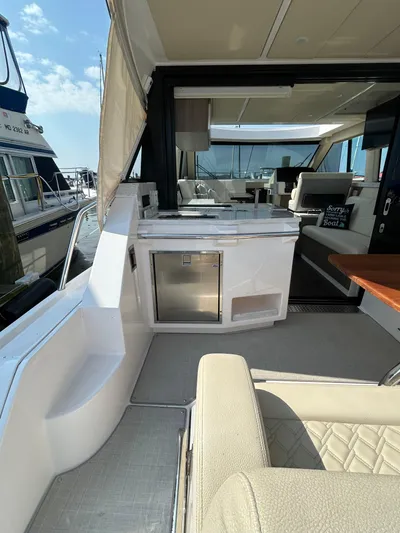  Yacht Photos Pics 2020 Regal 38 Grande Coupe yacht interior with seating and kitchenette, docked at marina.