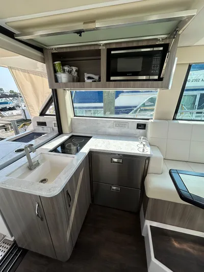  Yacht Photos Pics Modern kitchen interior of 2020 Regal 38 Grande Coupe yacht with sink, stove, and microwave.