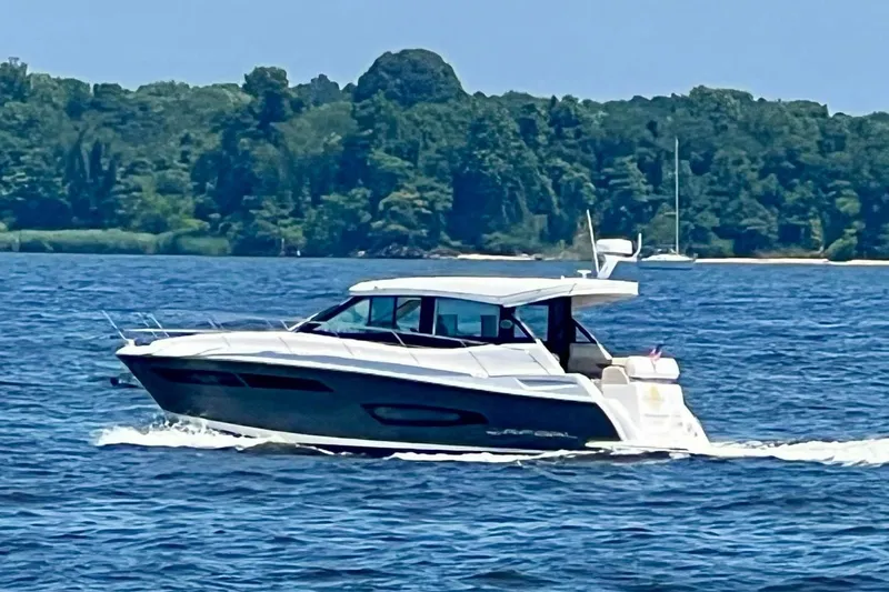  Yacht Photos Pics 2020 Regal 38 Grande Coupe cruising on a scenic lake with lush green shoreline.