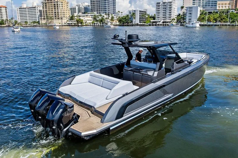 Not His Yacht Photos Pics 2024 Vanquish Yachts 40 cruising on a sunny waterfront with modern buildings in the background.