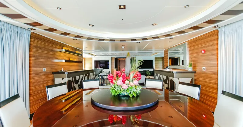 W Yacht Photos Pics Luxurious Feadship yacht interior, featuring elegant wood paneling and a floral centerpiece on a dining table.