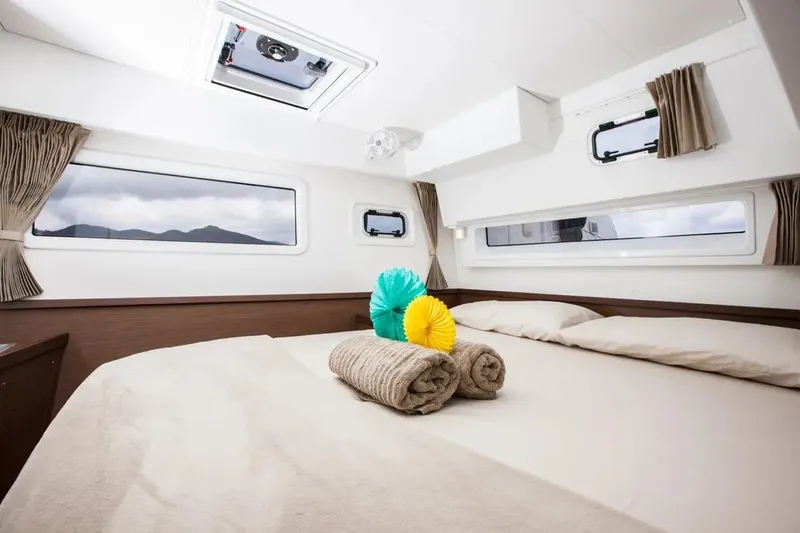  Yacht Photos Pics Luxurious cabin interior of 2020 Lagoon 42 catamaran with cozy bedding and scenic windows.