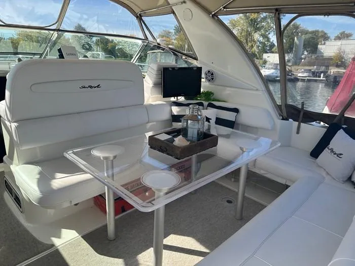 L'eternel Yacht Photos Pics 1998 Sea Ray 400 Sundancer interior with white seating, glass table, and marina view.