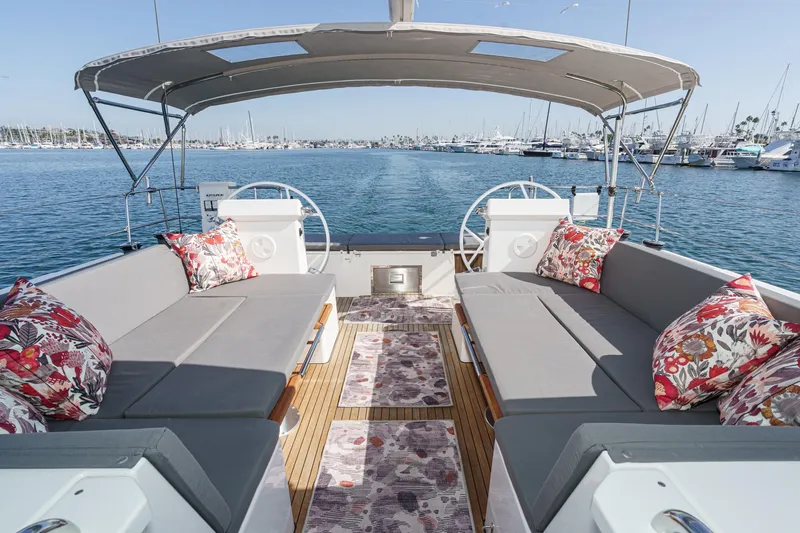 Tuanis Yacht Photos Pics Luxurious 2023 Bavaria C50 yacht interior with plush seating and vibrant cushions, docked in a marina.