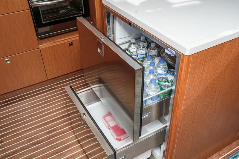 Tuanis Yacht Photos Pics Modern Bavaria C50 yacht kitchen with open drawer fridge, stocked with bottled water and drinks.