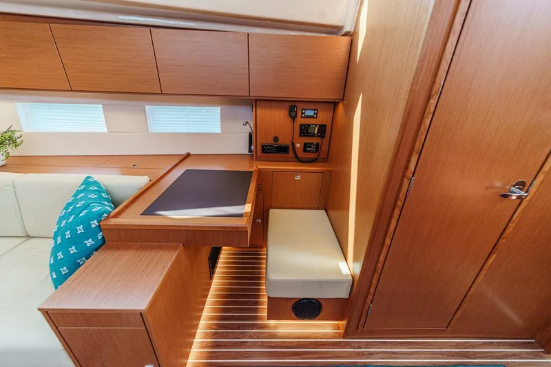 Tuanis Yacht Photos Pics 2023 Bavaria C50 yacht interior with wooden cabinetry, navigation station, and cushioned seating.