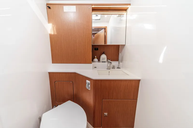 Tuanis Yacht Photos Pics Modern bathroom interior of 2023 Bavaria C50 yacht with wooden cabinetry and sleek fixtures.