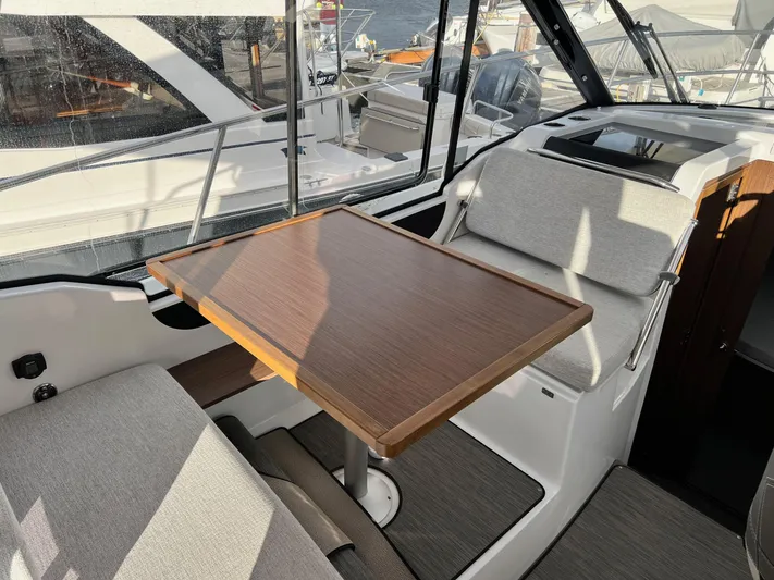  Yacht Photos Pics 2023 Jeanneau NC 895 interior with wooden table and cushioned seating.