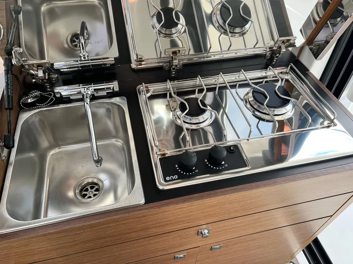  Yacht Photos Pics Compact kitchen area in 2023 Jeanneau NC 895 boat with stove and sink.