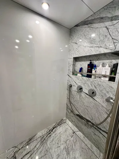  Yacht Photos Pics Luxurious marble shower in 2024 Sirena 68 yacht with modern fixtures and recessed shelf.