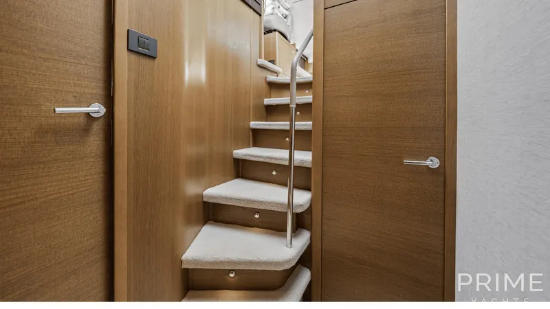  Yacht Photos Pics Interior staircase of 2019 Princess F49 yacht with wooden finish and carpeted steps.