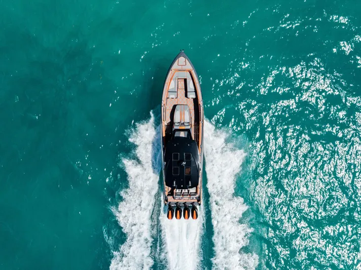 Casual Acquaintance Yacht Photos Pics 2024 Deep Impact 399 Sport boat cruising on turquoise water, aerial view.
