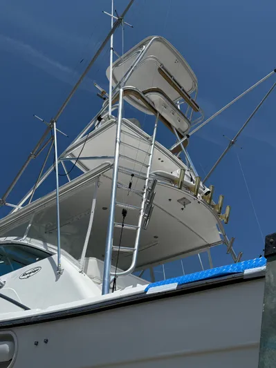 Side Chick Yacht Photos Pics 2002 Rampage 38 Express boat with tower against blue sky.