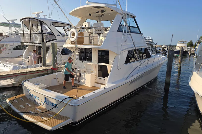 Buenos Aires Yacht Photos Pics 2003 Riviera 48 Flybridge yacht docked at marina with person on deck.