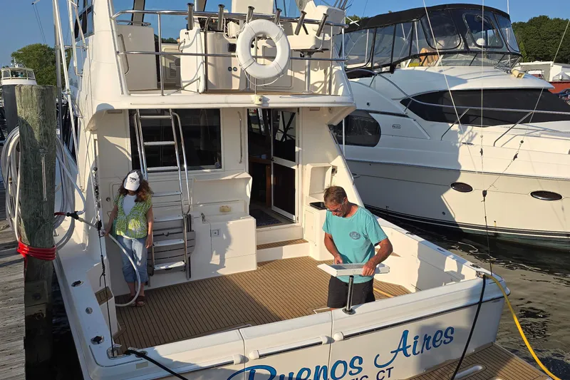 Buenos Aires Yacht Photos Pics 2003 Riviera 48 Flybridge yacht docked, with two people on deck, sunny day.