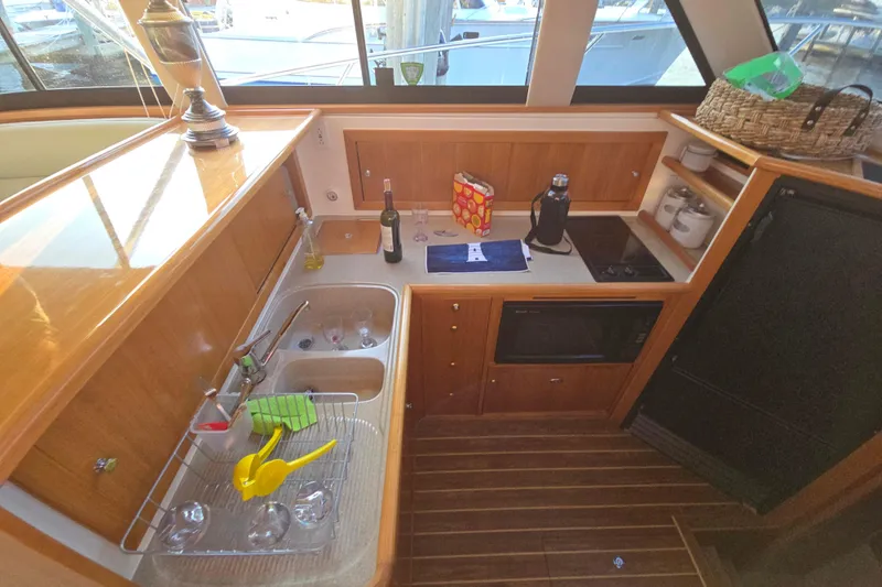 Buenos Aires Yacht Photos Pics 2003 Riviera 48 Flybridge yacht kitchen with wooden cabinetry, sink, and appliances.