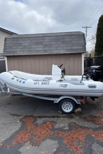  Yacht Photos Pics Inflatable boat on trailer, parked beside a shed, overcast sky.