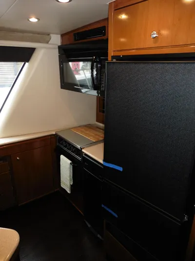  Yacht Photos Pics 2005 Meridian PILOTHOUSE kitchen with black appliances and wooden cabinetry.