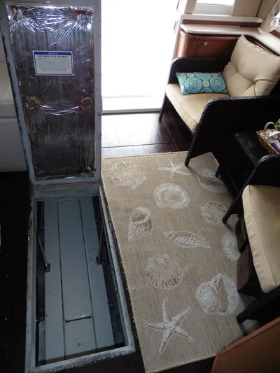  Yacht Photos Pics Open hatch in 2005 Meridian PILOTHOUSE interior, revealing storage space, with coastal-themed rug nearby.