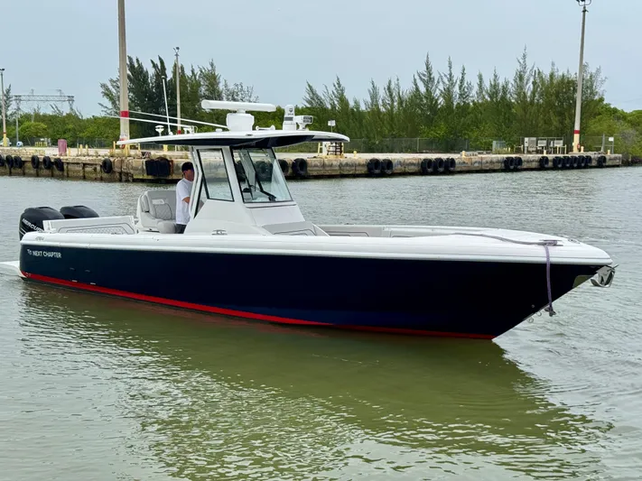  Yacht Photos Pics 2018 Intrepid 327 Center Console boat on calm water near a dock.