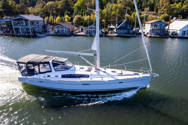 Resiliance Yacht Photos Pics 2013 Beneteau Oceanis 50 sailing near waterfront homes on a sunny day.