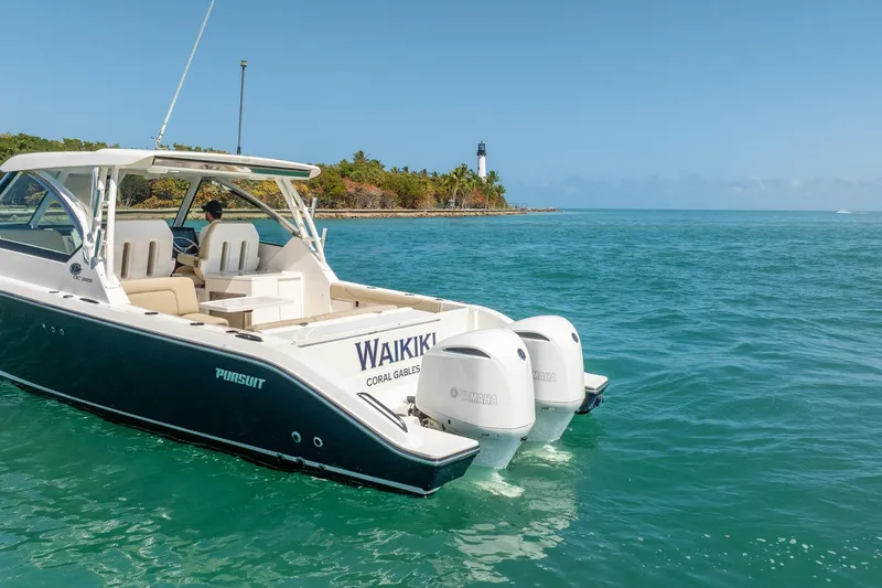 Waikiki Yacht Photos Pics 2017 Pursuit DC 325 Dual Console boat cruising near a lighthouse on clear blue waters.
