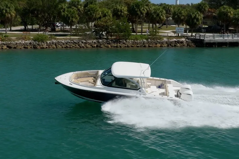 Waikiki Yacht Photos Pics 2017 Pursuit DC 325 Dual Console boat cruising on turquoise water near a lush shoreline.