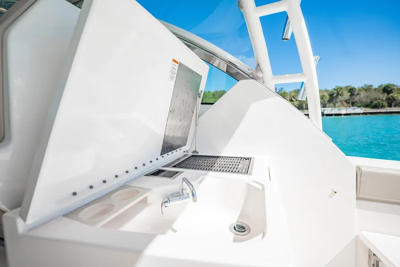 Waikiki Yacht Photos Pics 2017 Pursuit DC 325 Dual Console boat interior with sink and grill, near turquoise water.