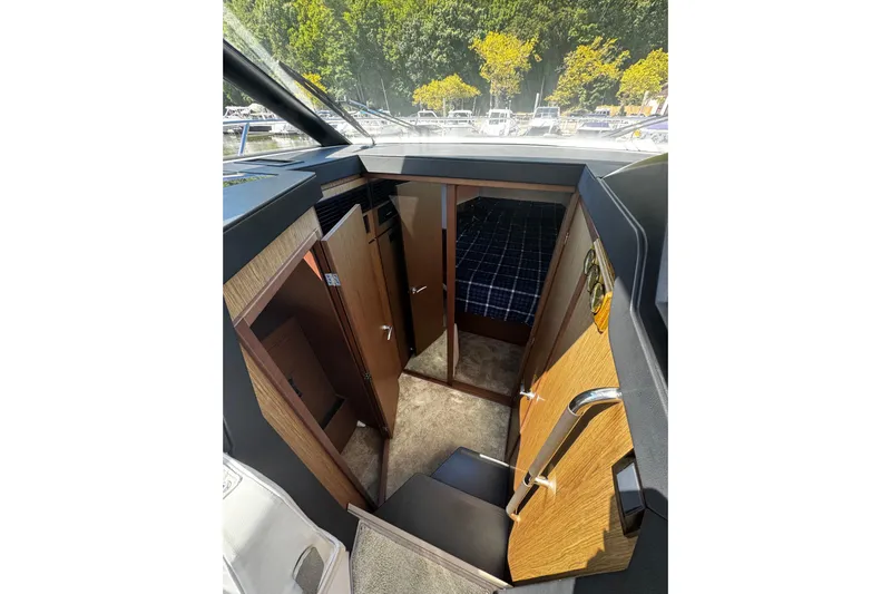  Yacht Photos Pics Interior view of 2019 Jeanneau NC33 boat cabin with wood finish and cozy sleeping area.