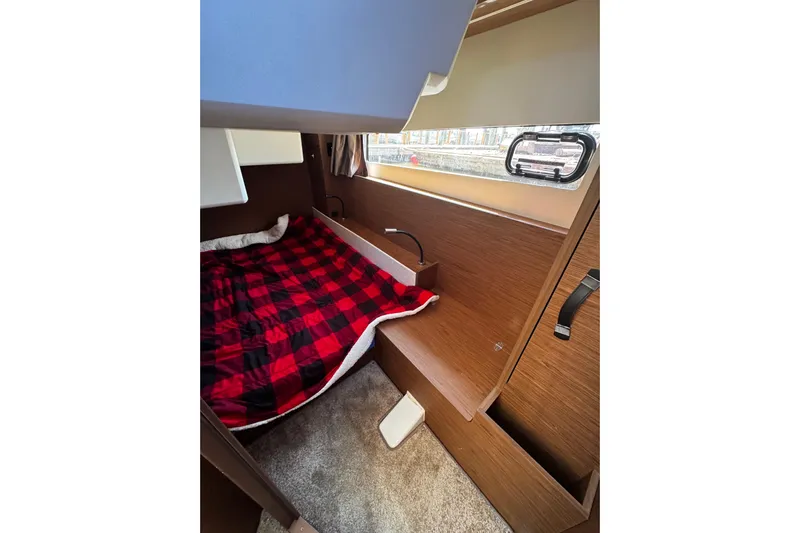  Yacht Photos Pics Cozy cabin interior of 2019 Jeanneau NC33 with plaid bedding and wooden accents.